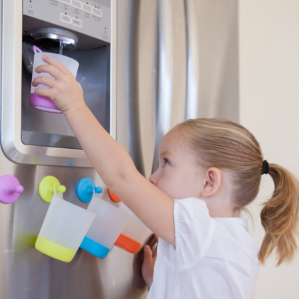 niña caucásica llenando un vaso de agua de la nevera